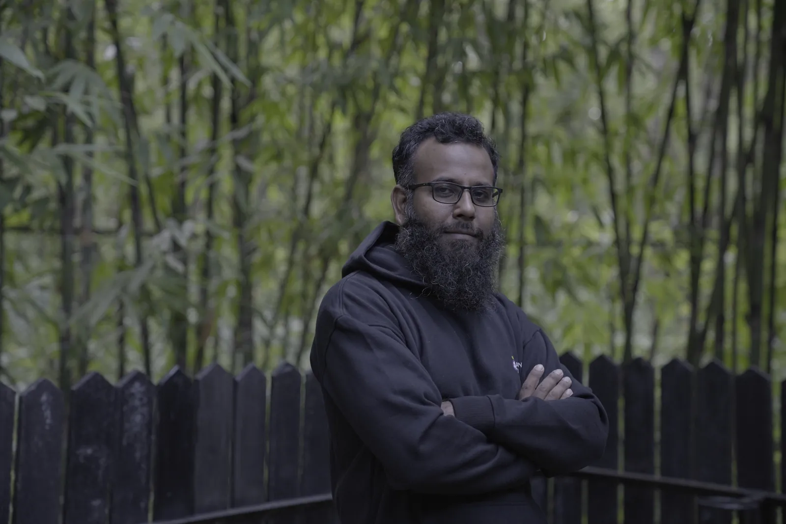 Arms-crossed portrait against a bamboo grove