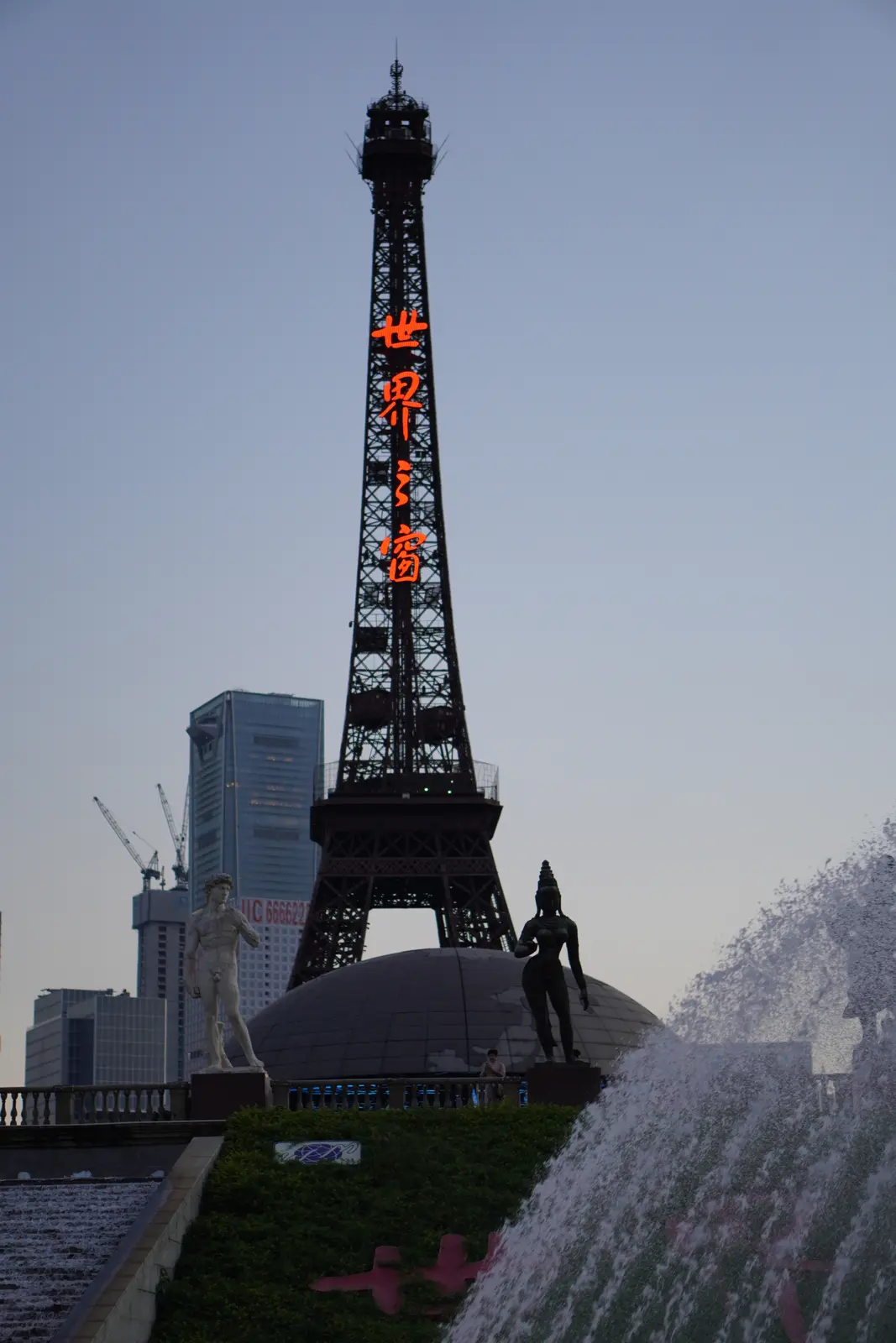 Replica Eiffel Tower above the park fountains at dusk