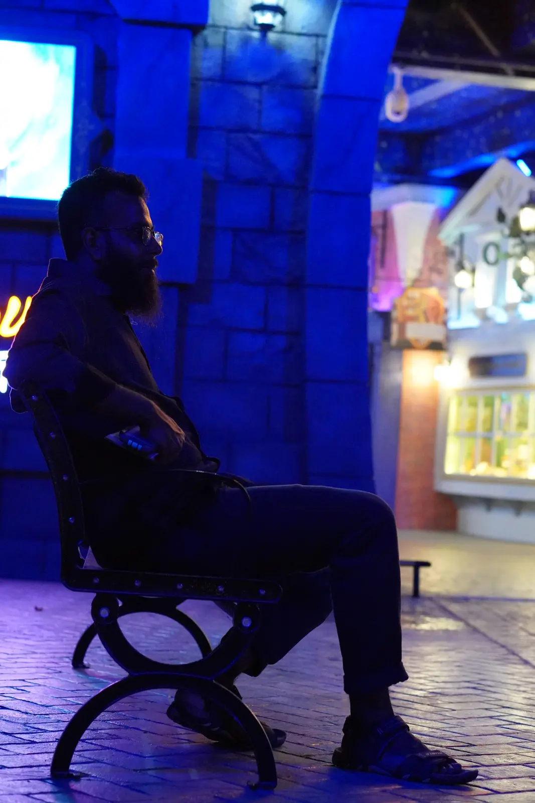 Sitting on a bench in a blue-lit night street, China