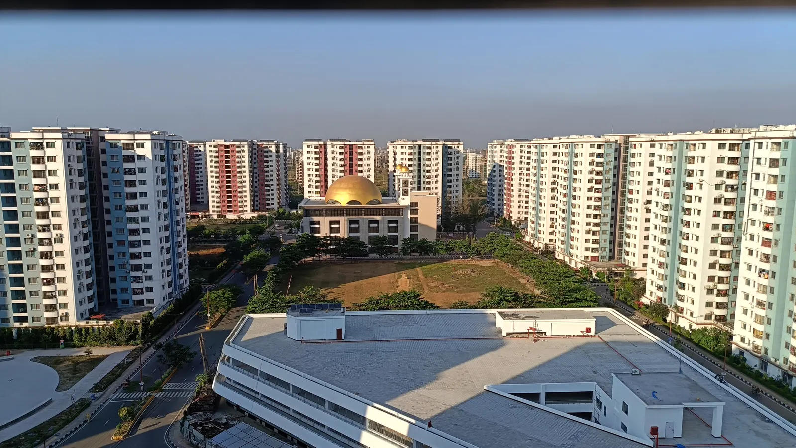 Apartment towers around a golden-domed mosque, seen from a rooftop in Dhaka