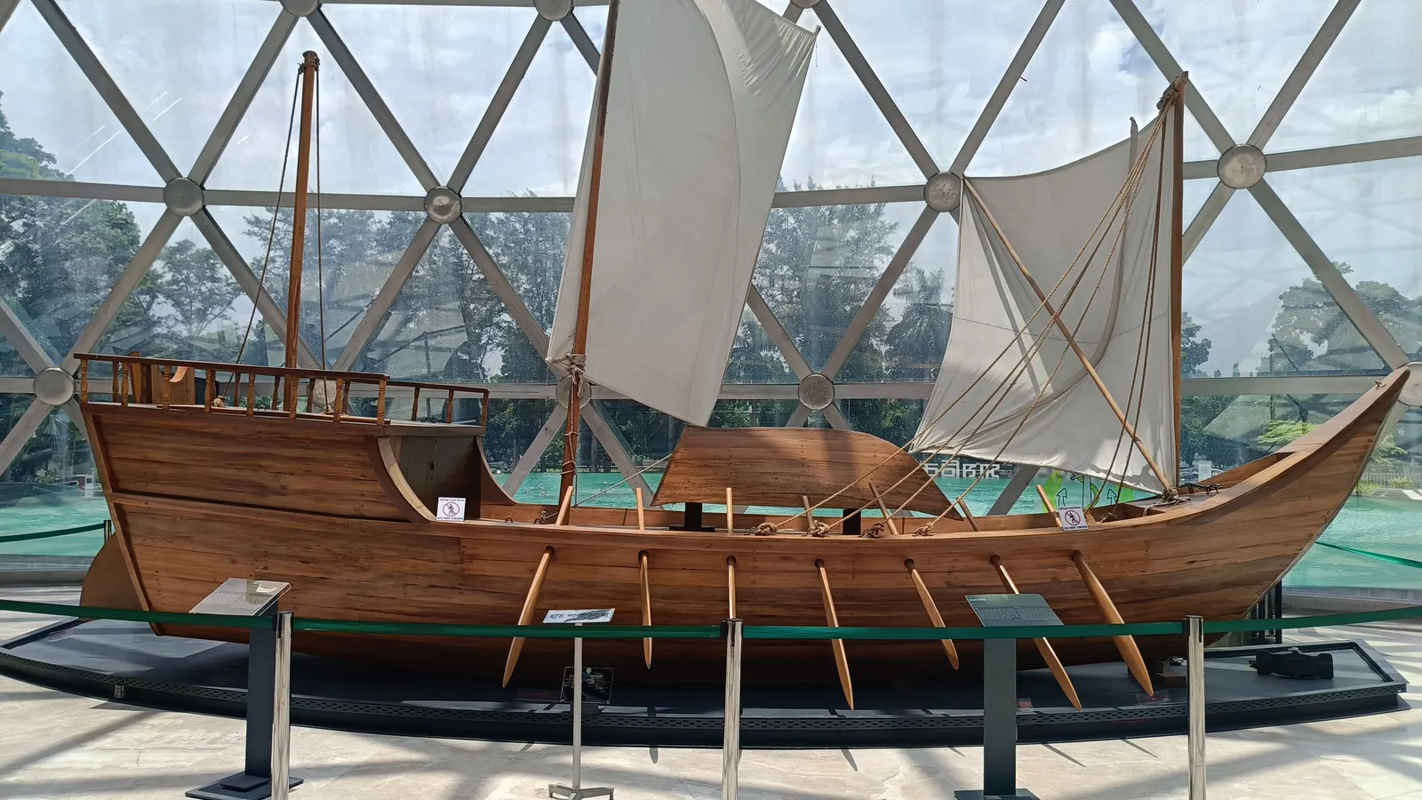 A full-size wooden sailing boat under the glass dome of the military museum