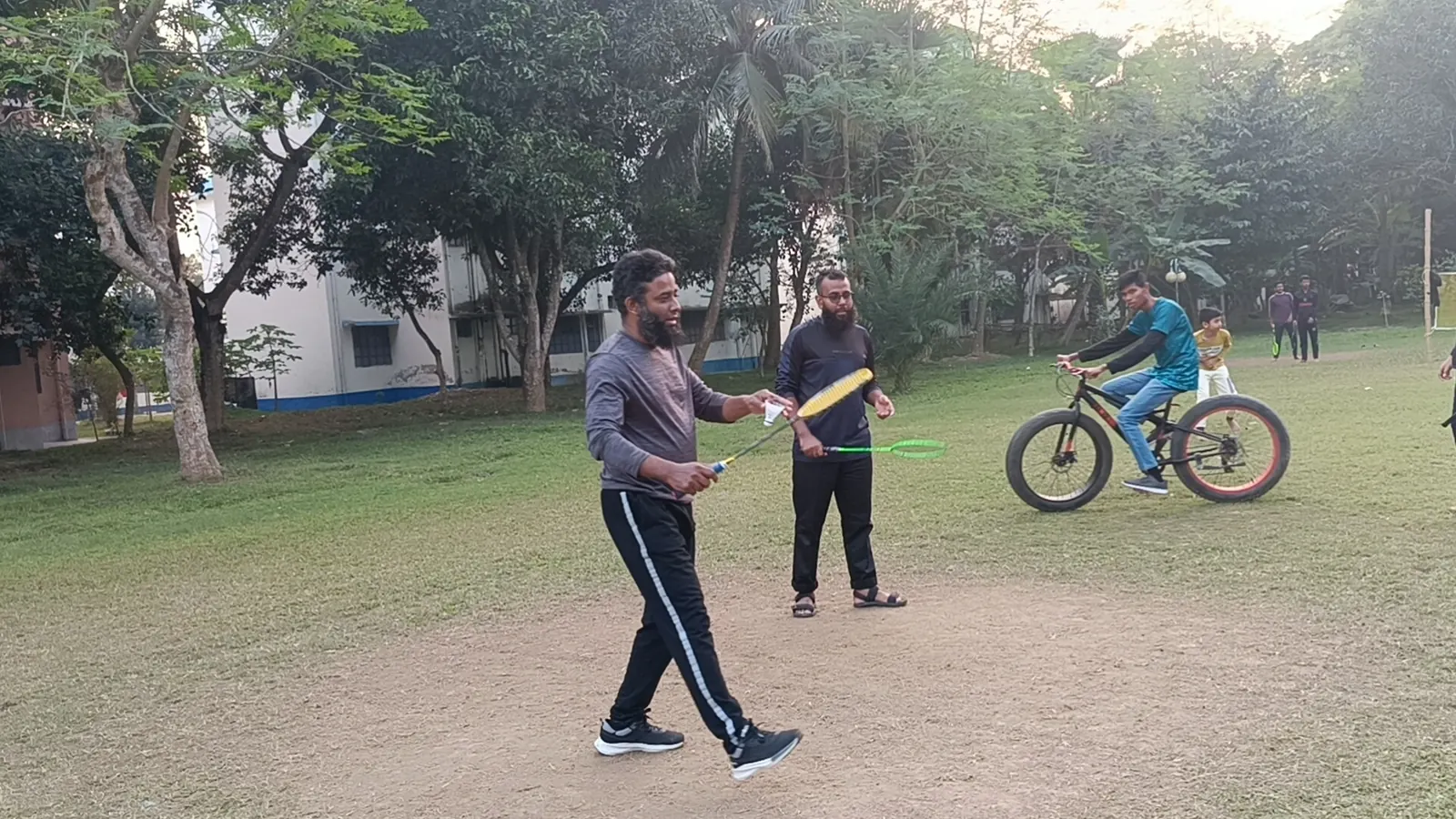 Winter badminton in the park while a child circles past on a bike