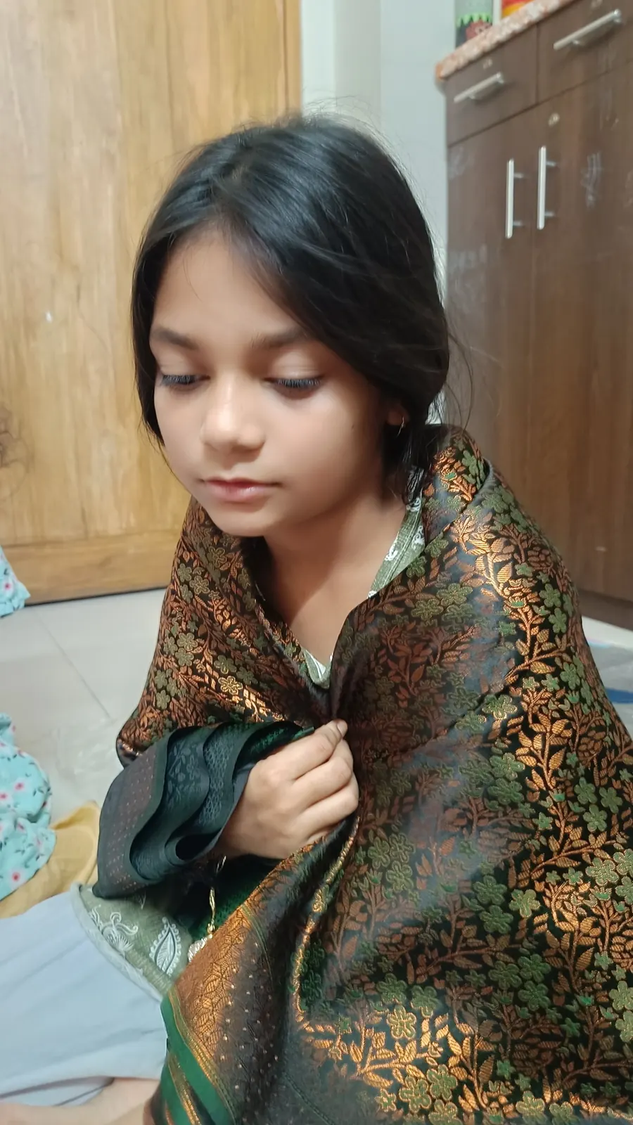 Wrapped in a gold-embroidered sari at home