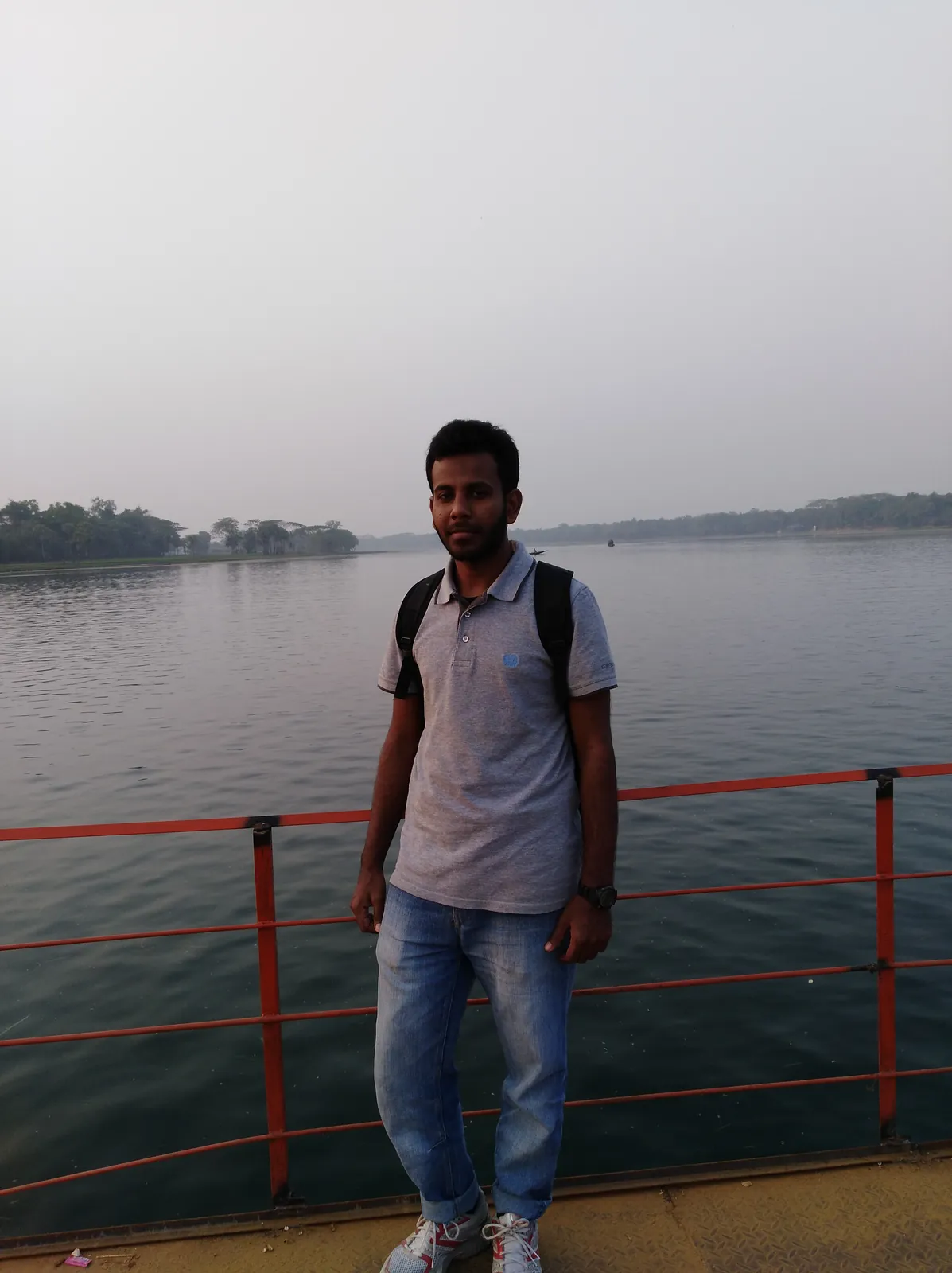 At the orange railing over the wide, calm river
