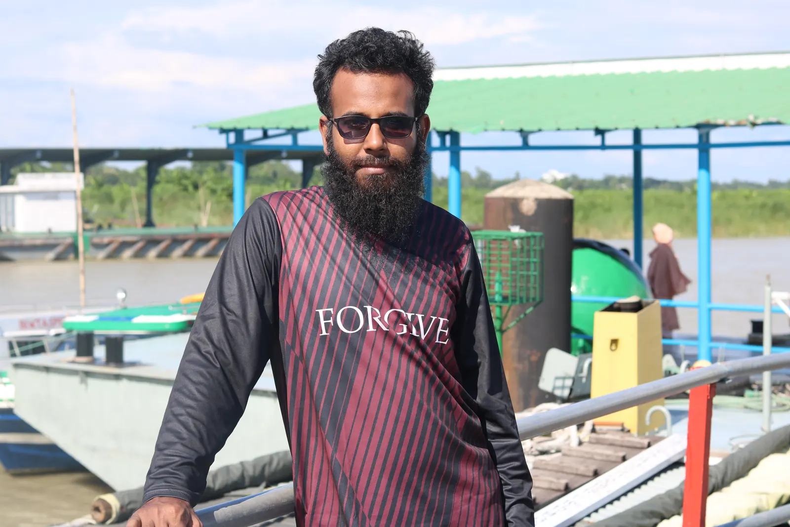 Leaning on the rail of the ferry ghat, barges moored behind