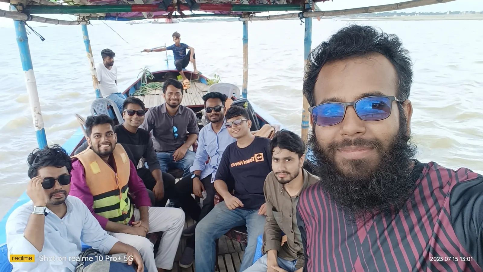 Group selfie on the boat, life jackets on, river wide behind