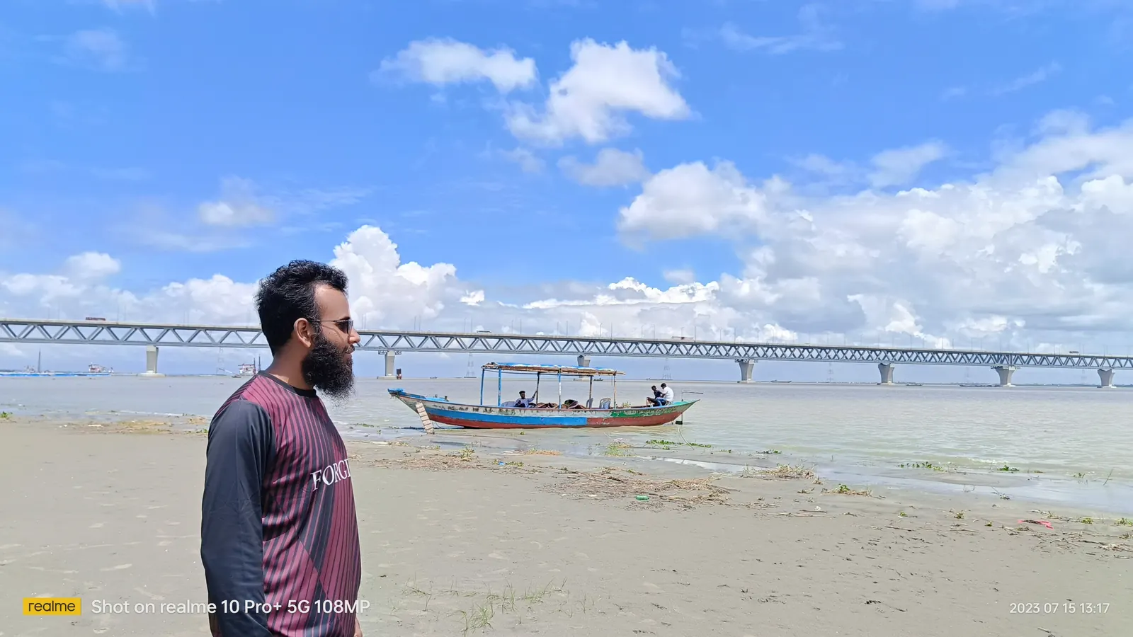 Standing on the sandbank as a boat drifts past the bridge