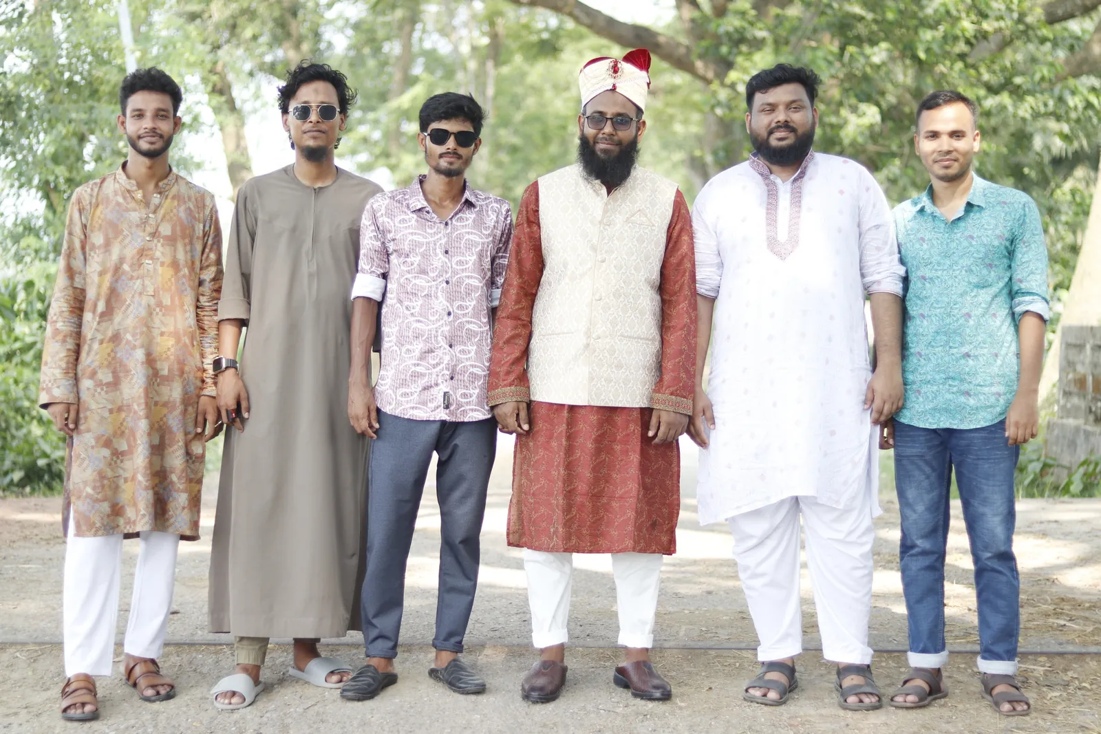 Lined up with friends in panjabis on a tree-lined rural road