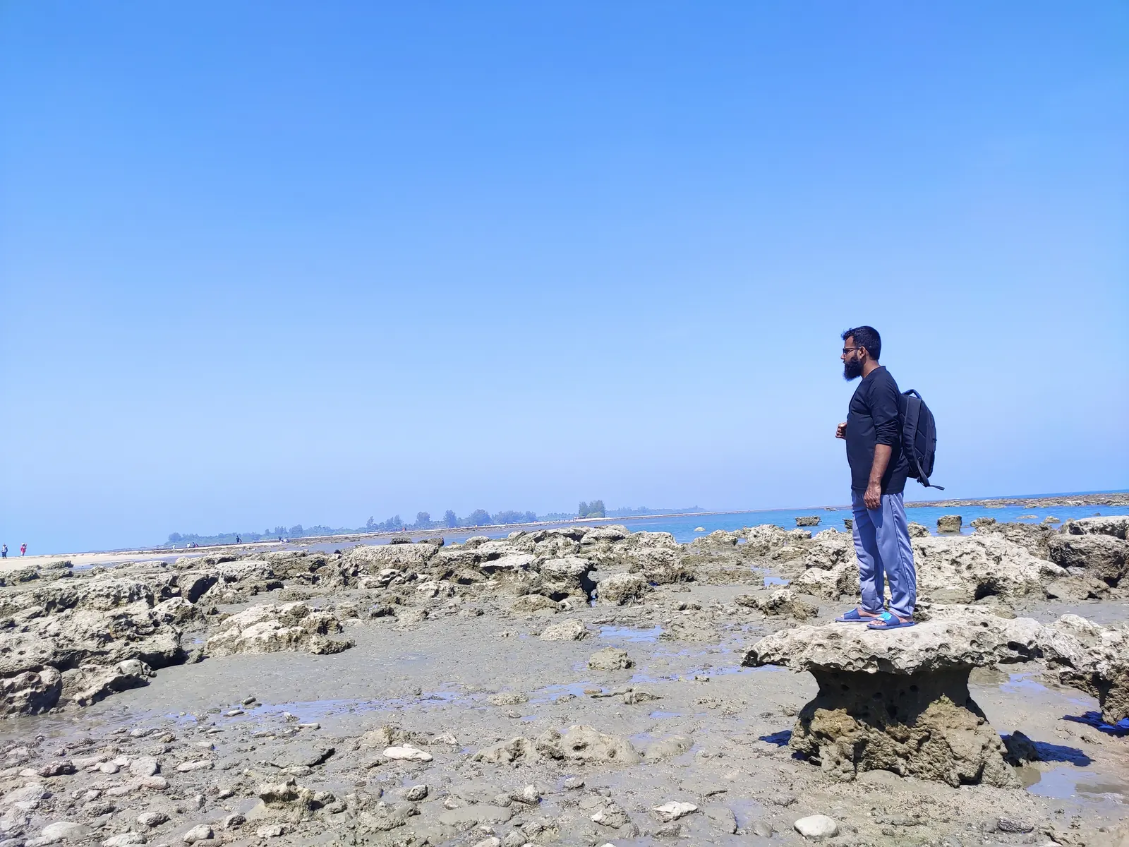 On a coral outcrop above the tide pools, backpack on