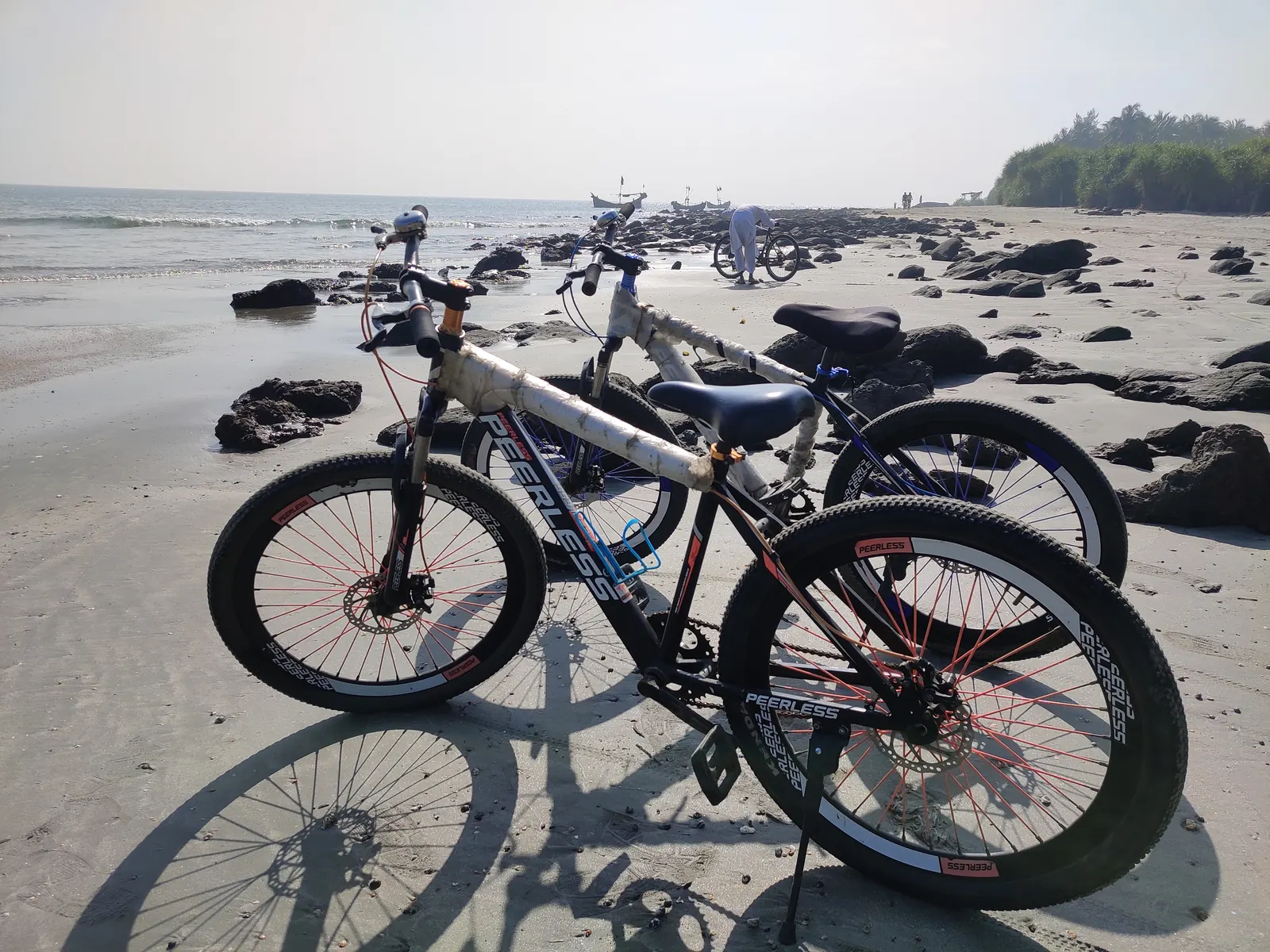 Two rented cycles parked on the sand at the rocky end of the beach