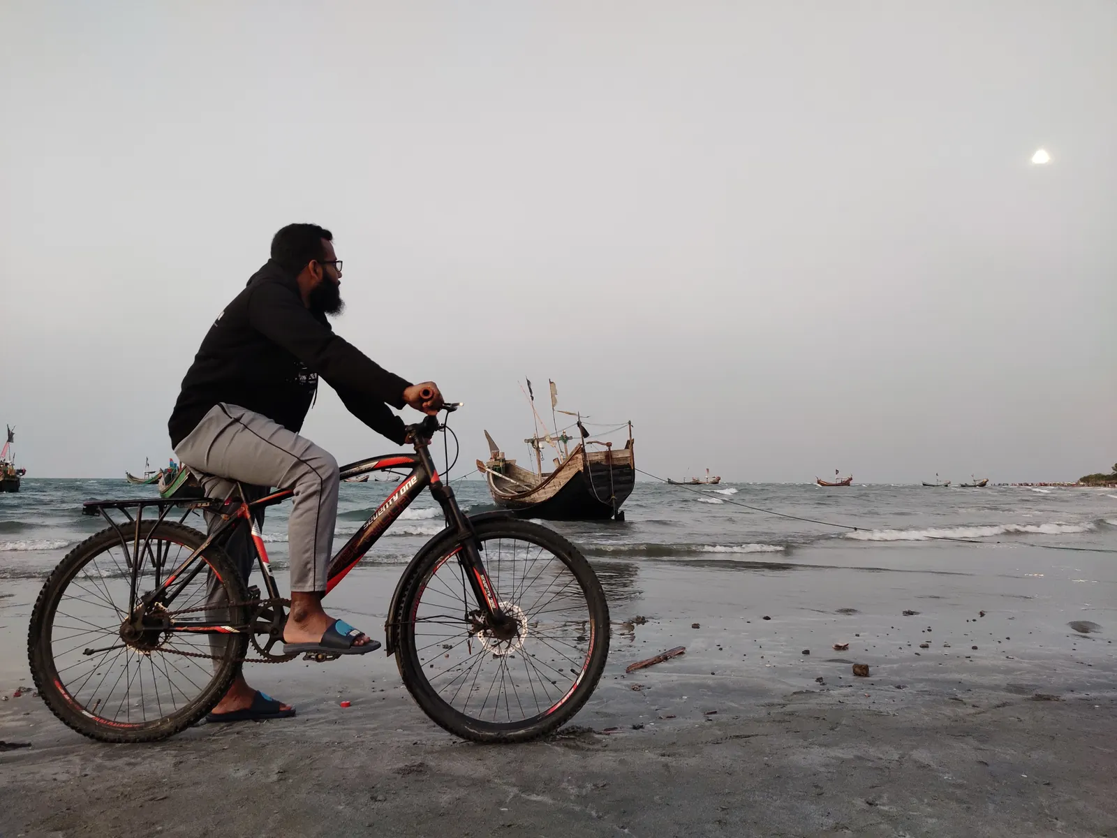 Riding along the wet sand past a moored wooden boat