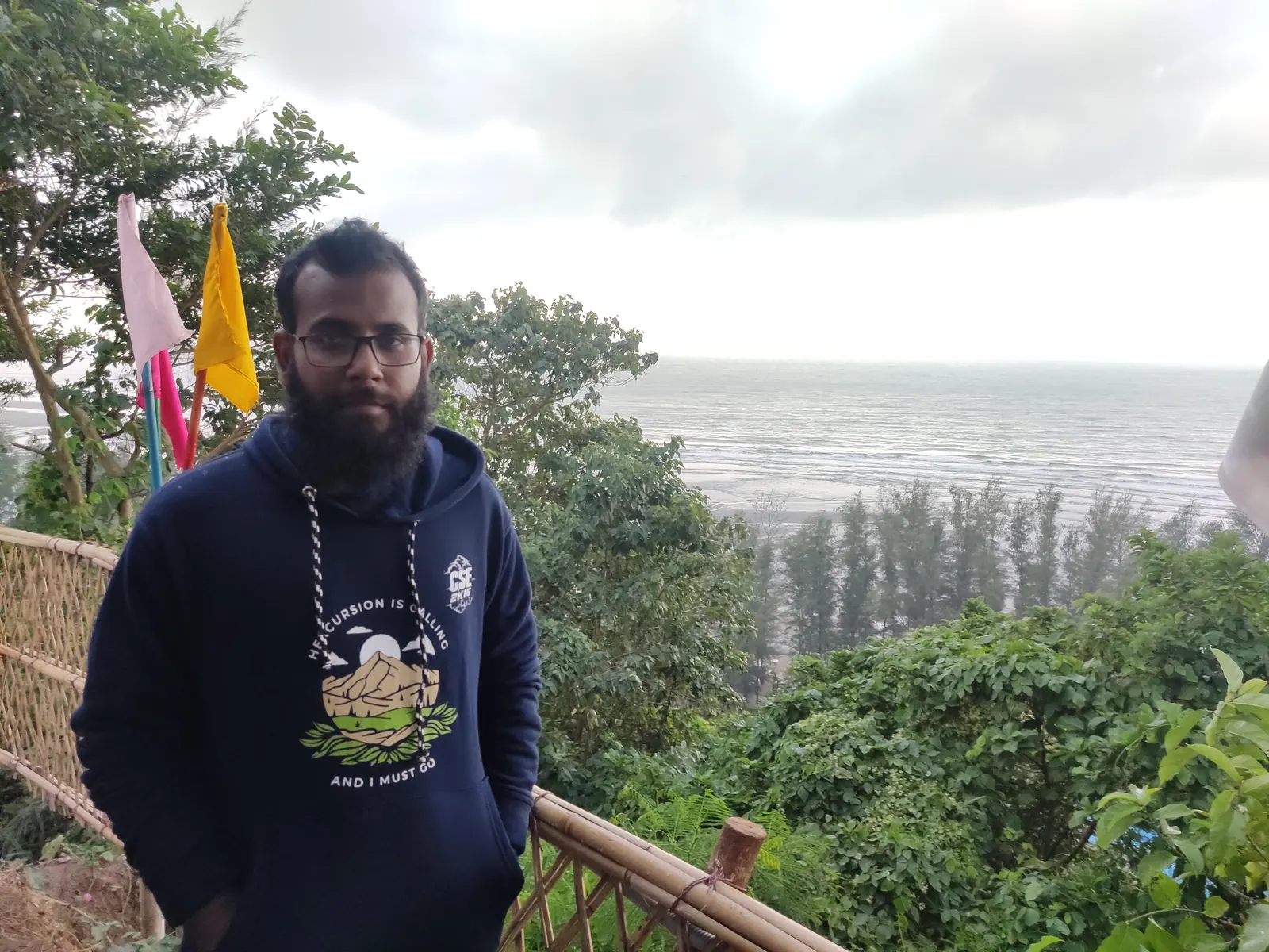 At the bamboo-railed viewpoint above the beach, flags snapping behind