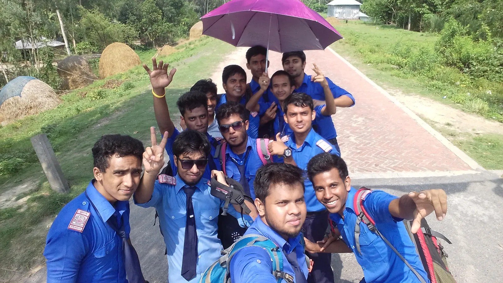 Schoolboys in uniform crowded under a purple umbrella on a brick road