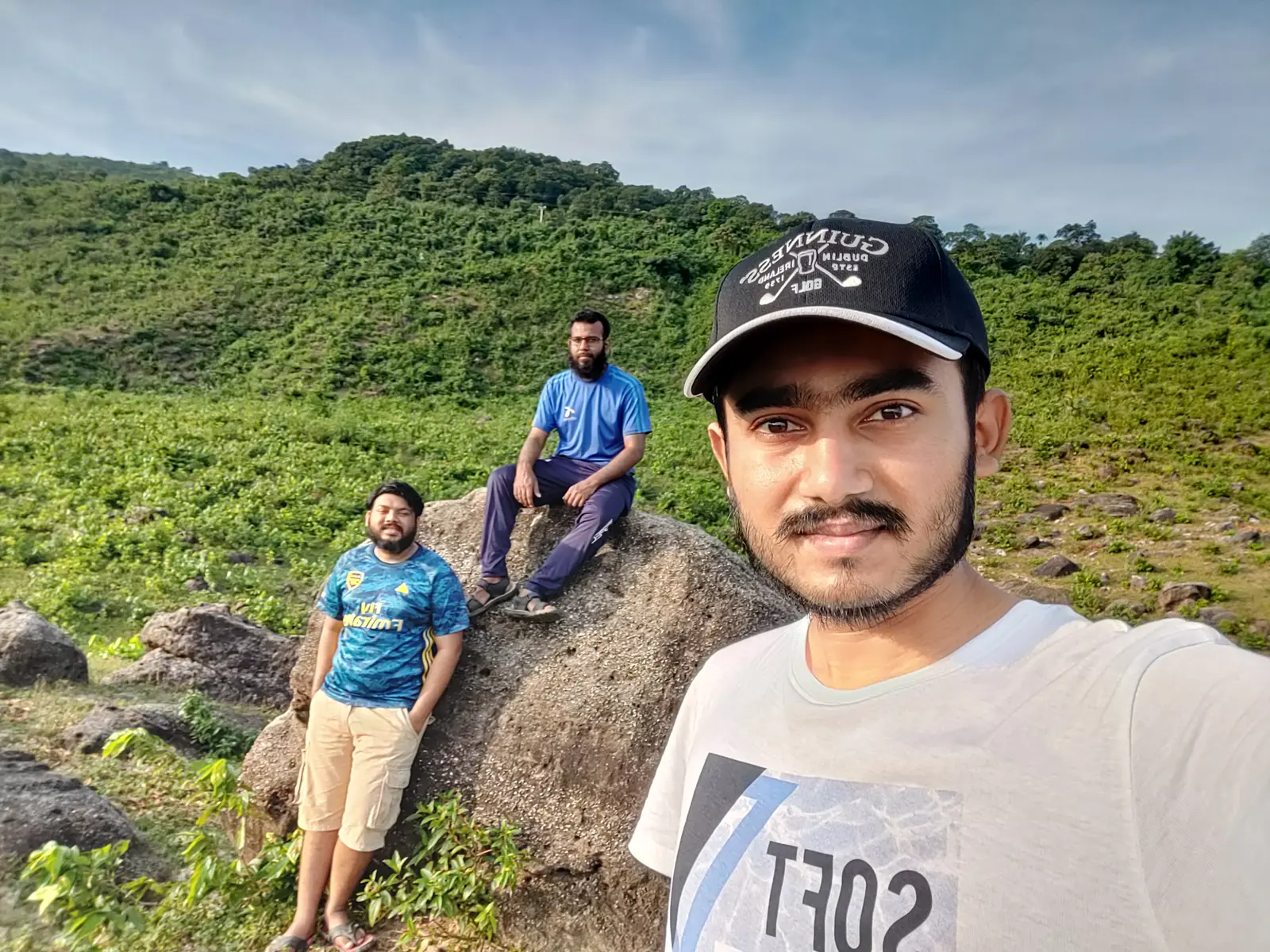 Group selfie on the boulders below a green hillside, Tanguar Haor