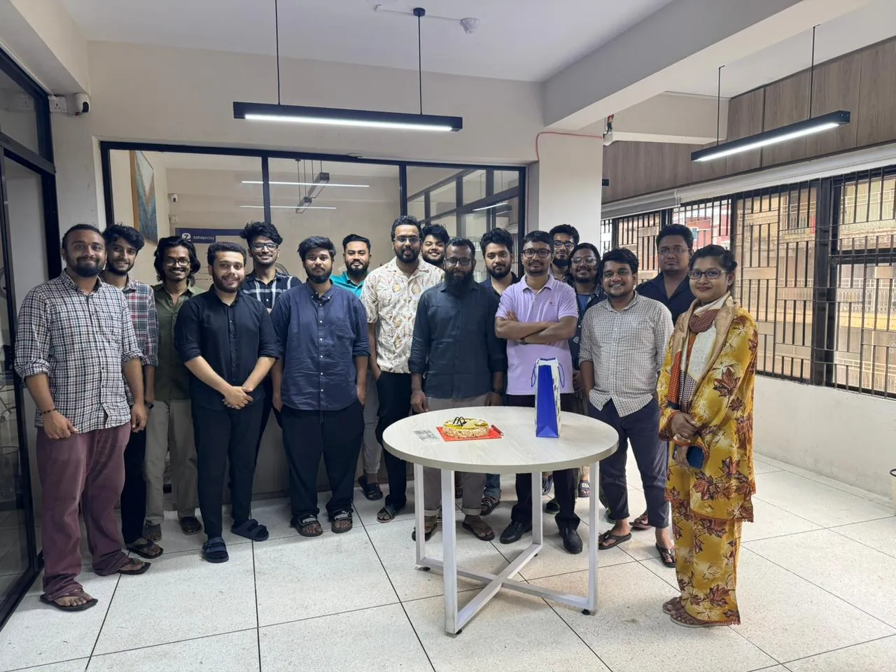 The whole office gathered around a celebration cake