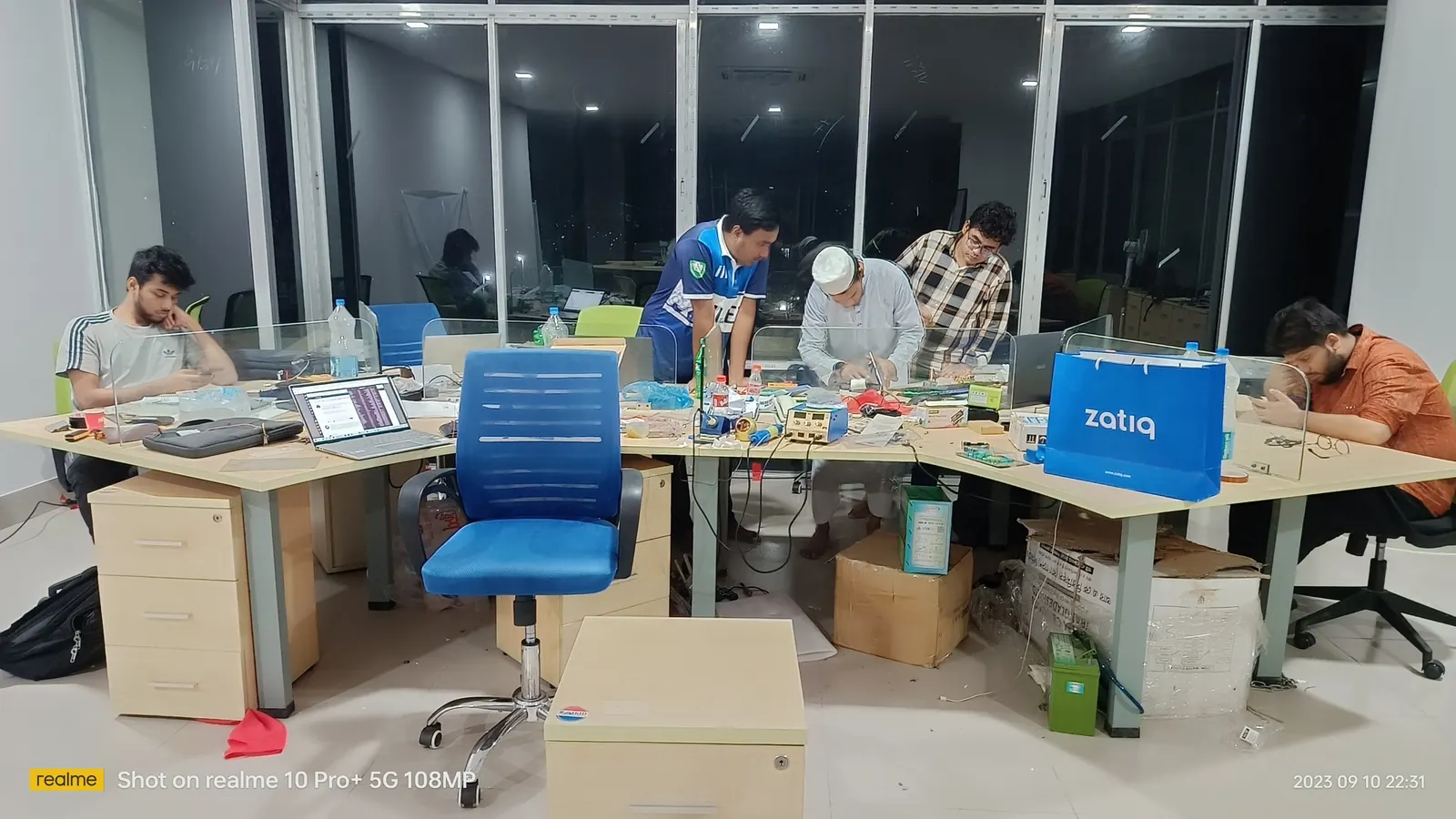The office late at night, desks buried under laptops and packing boxes